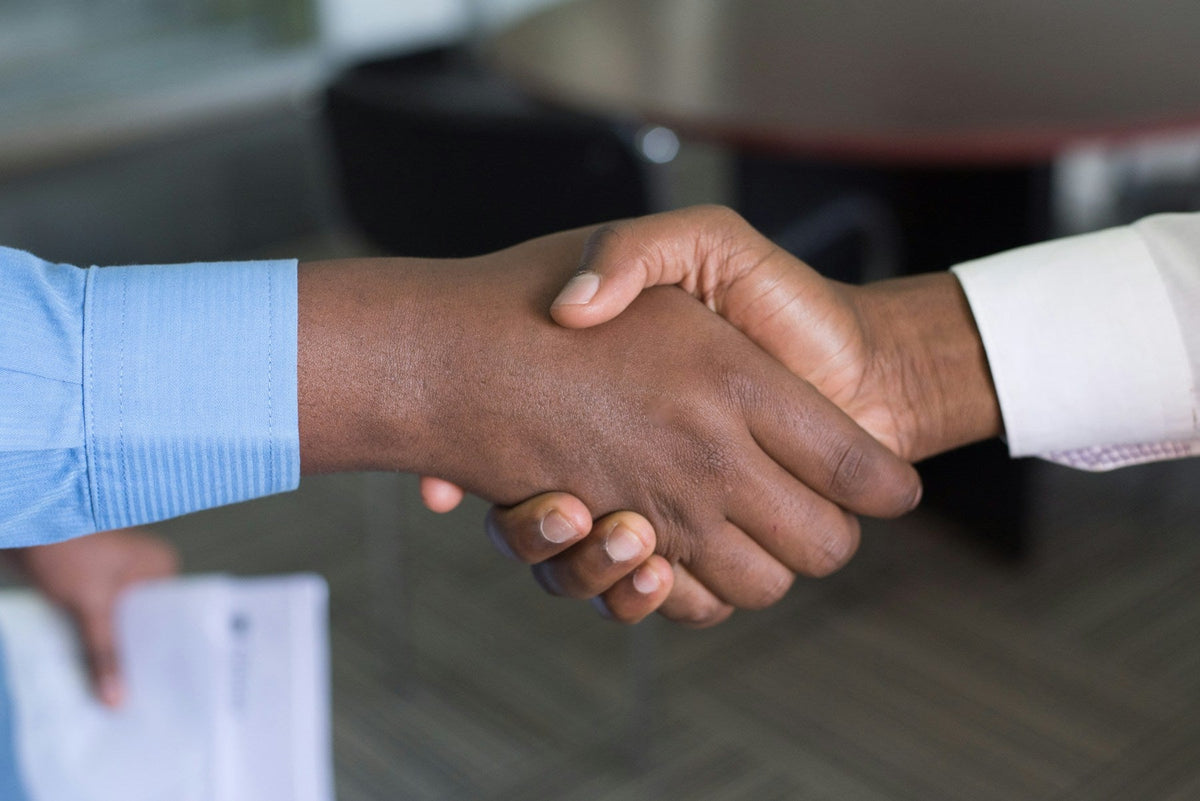 Two people shaking hands across a desk